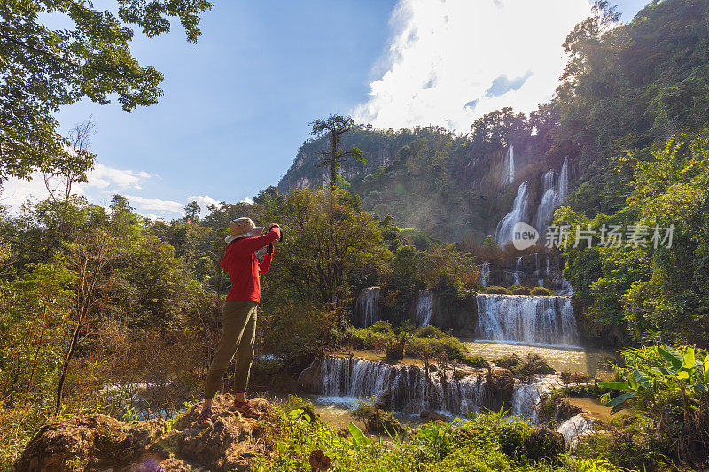 亚洲女人在拍摄美丽的瀑布(Thi Lor Su)在德，泰国。